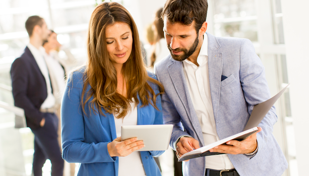Imagen de una mujer junto a un hombre revisando información en una tablet.